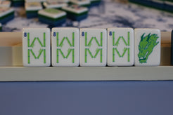 Close-up of Mahjong tiles with green characters and a dragon symbol.